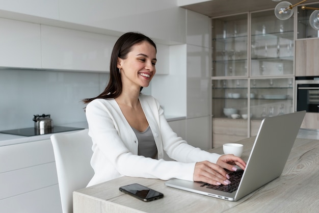 Tiro medio sonriente mujer que trabaja en la computadora portátil