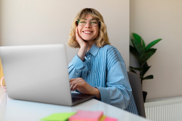 Tiro medio sonriente mujer que trabaja en la computadora portátil