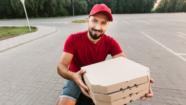 Foto gratuita tiro medio sonriente repartidor con pizza