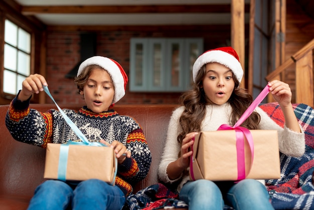 Tiro medio sorprendido hermano y hermana abriendo regalos