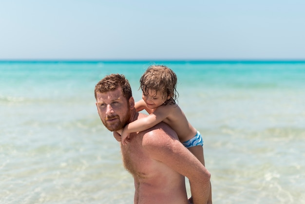 Foto gratuita tiro medio sosteniendo a su hijo y apartando la mirada.