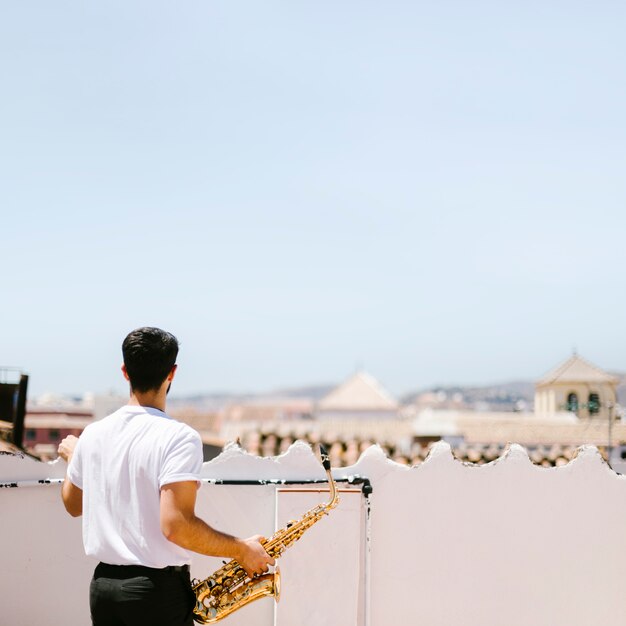 Tiro medio vista trasera hombre con saxofón