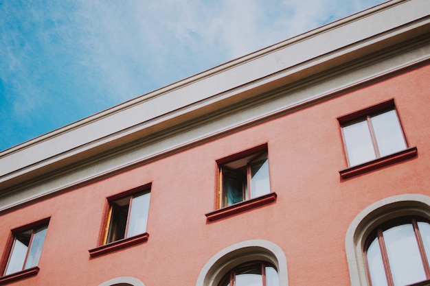 Foto gratuita tiro de primer plano de ángulo bajo de un edificio rosa con ventanas