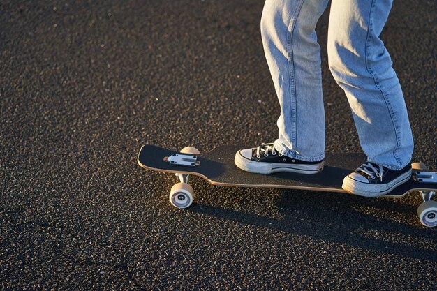 Tiro recortado de piernas en longboard skater girl montando su patineta en la calle adolescente femenina en cru