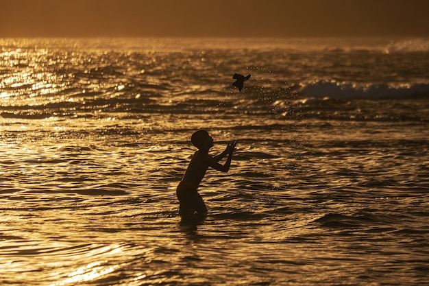 Tiro de silueta de un niño jugando en la playa