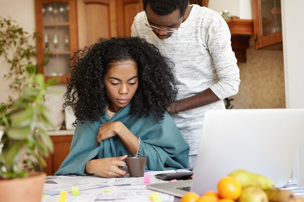 Tiro sincero de la joven pareja afroamericana trabajando juntos a través de las finanzas