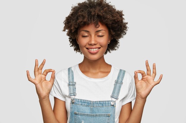 Tiro sincero de mujer bonita negra muestra gesto bien o zen