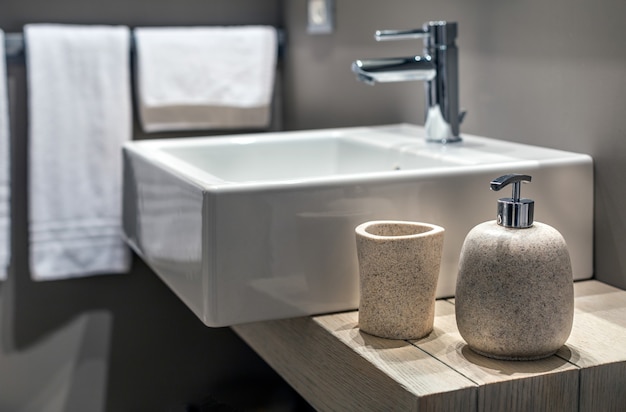 Foto gratuita tiro superficial de un fregadero moderno al lado de la botella en el baño.