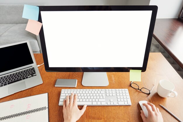 Tiro superior recortado de manos femeninas escribiendo en el teclado, sentado en la oficina