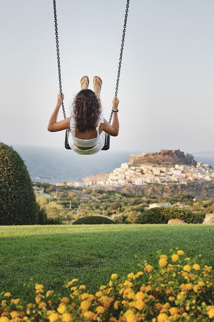 Foto gratuita tiro vertical de alegre mujer balanceándose en un campo de hierba con fondo borroso ideal para blogs