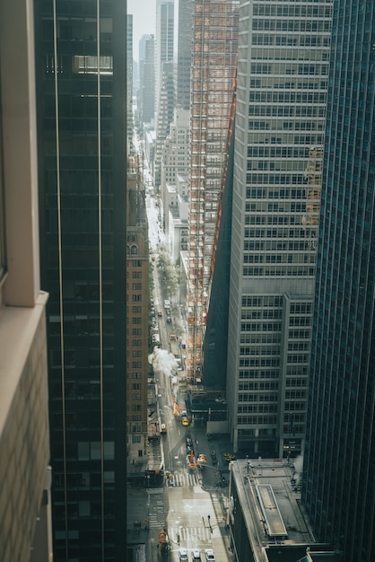 Tiro vertical de alto ángulo de una larga calle de la ciudad entre modernos rascacielos