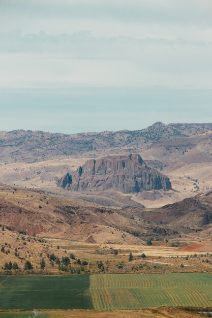 Tiro vertical de alto ángulo de un paisaje con acantilados rocosos y un campo de hierba verde