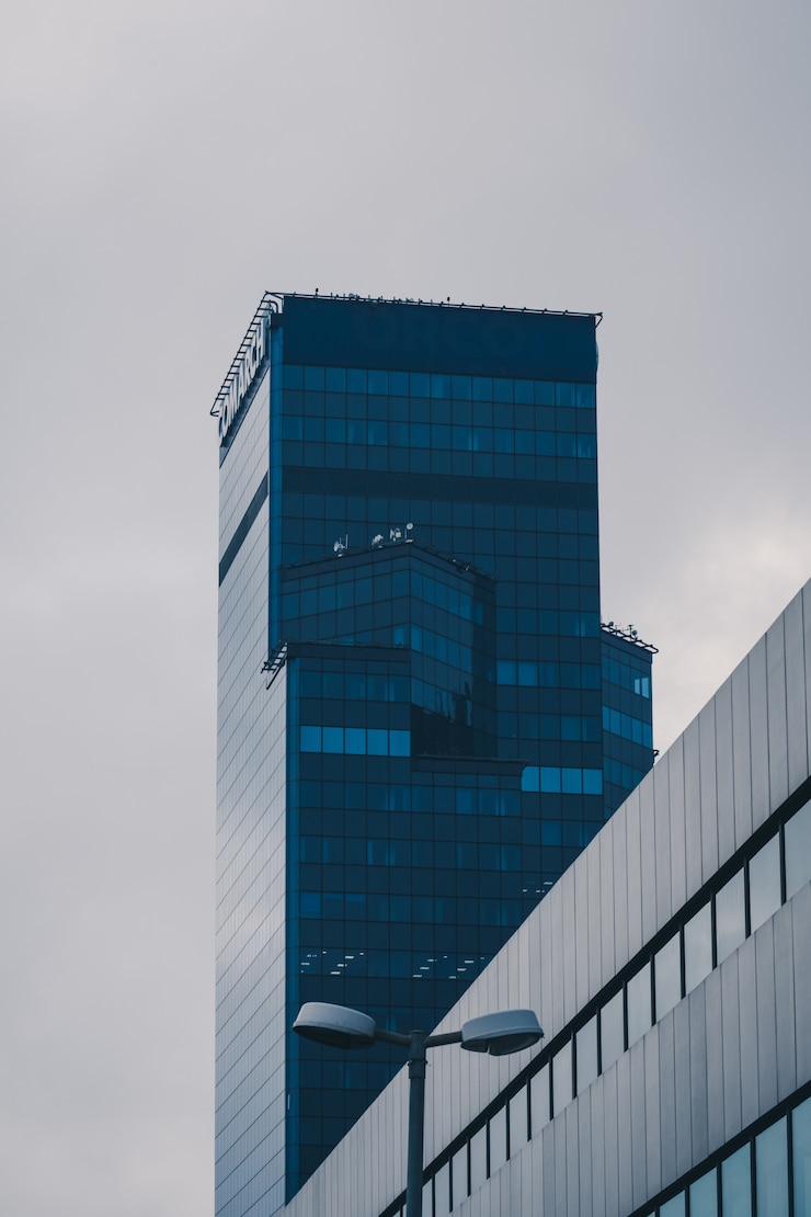 Foto gratuito tiro vertical de ángulo bajo de un edificio de gran altura en una fachada de cristal bajo el cielo despejado