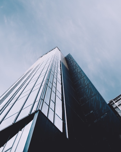 Tiro vertical de ángulo bajo de un edificio de gran altura en una fachada de vidrio