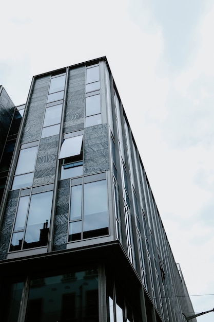 Foto gratuita tiro vertical de ángulo bajo de un hermoso edificio de cristal capturado durante el día