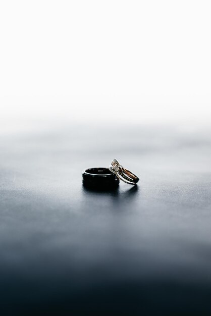 Tiro vertical de los anillos de boda de la novia y el novio en una superficie gris