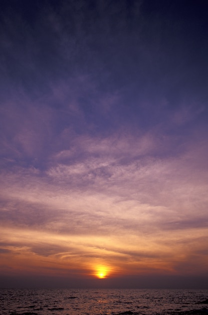 Foto gratuita tiro vertical de un cielo púrpura y amarillo sobre el mar al atardecer