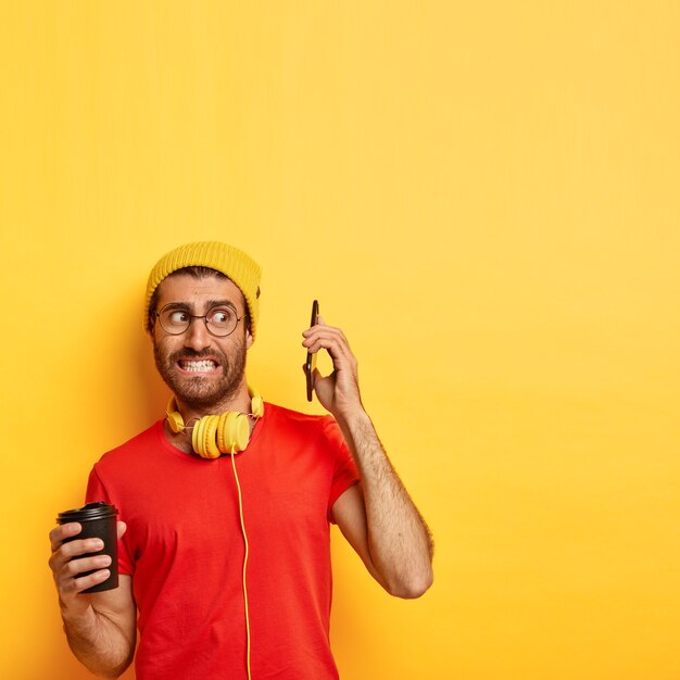 Tiro vertical de desconcertado hombre nervioso evita hablar por teléfono inteligente