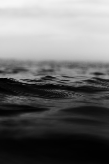 Tiro vertical en escala de grises de pequeñas olas de mar agitado