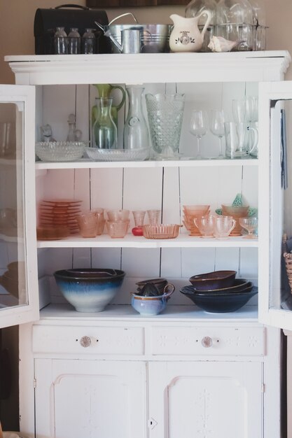 Tiro vertical de un estante blanco con diferentes tipos de utensilios de cocina de cerámica y vidrio.
