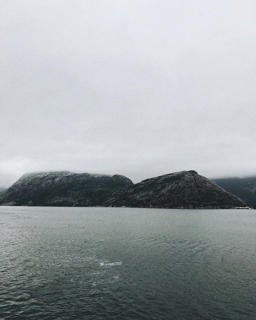 Foto gratuita tiro vertical de formaciones rocosas a la orilla del mar bajo el cielo sombrío