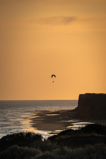 Tiro vertical de la hermosa puesta de sol sobre el mar Parapente al atardecer