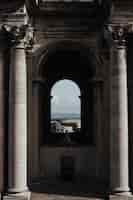 Foto gratuita tiro vertical del interior de un templo con ventana de arco y el hermoso paisaje urbano en segundo plano.