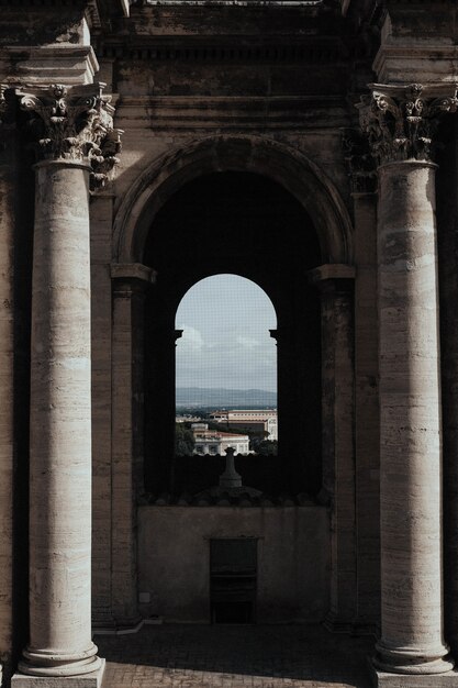 Foto gratuita tiro vertical del interior de un templo con ventana de arco y el hermoso paisaje urbano en segundo plano.