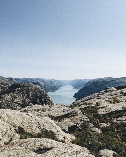 Tiro vertical de un lago rodeado de formaciones rocosas bajo el cielo despejado