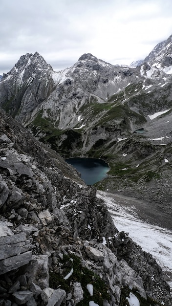 Tiro vertical de un lago rodeado de montañas bajo un cielo nublado