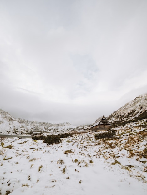 Tiro vertical largo de un paisaje invernal con una pequeña cabaña en las montañas Tatra en Polonia