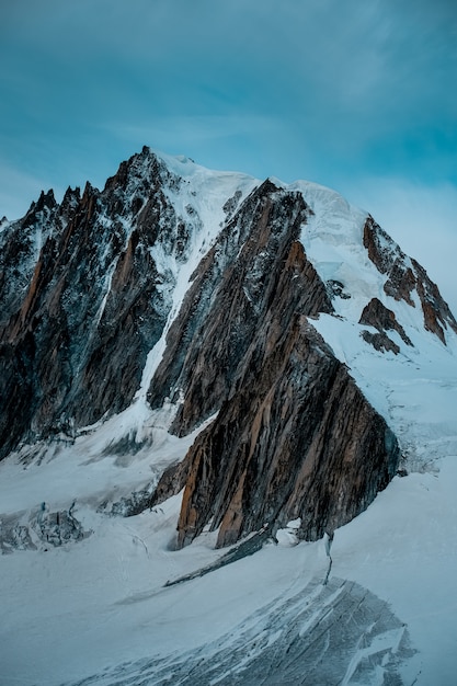 Tiro vertical de una montaña nevada con un cielo azul