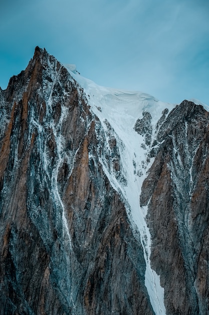 Tiro vertical de una montaña nevada con un cielo despejado en el fondo