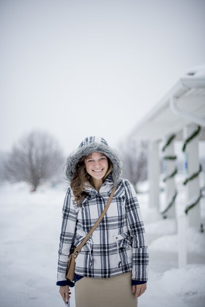 Tiro vertical de una mujer con una chaqueta de invierno en un día nevado mientras sonríe