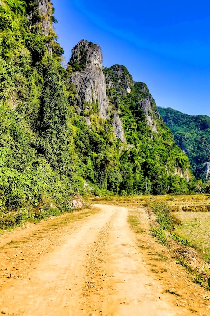 Foto gratuita tiro vertical oa un camino en la ladera de las montañas durante el día