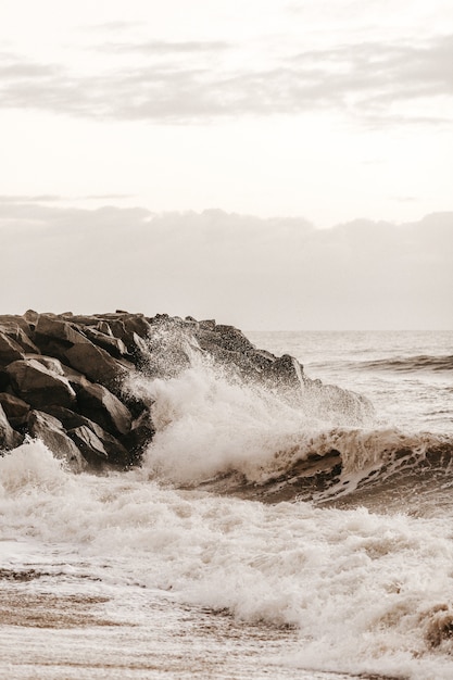 Tiro vertical de olas chapoteando en la costa rocosa durante el día