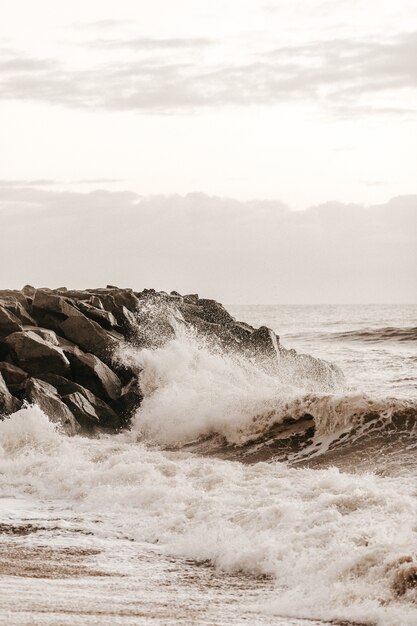 Tiro vertical de olas chapoteando en la costa rocosa durante el día