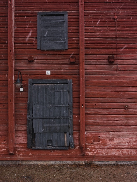 Tiro vertical de una pared de madera roja con puertas de madera gris en invierno