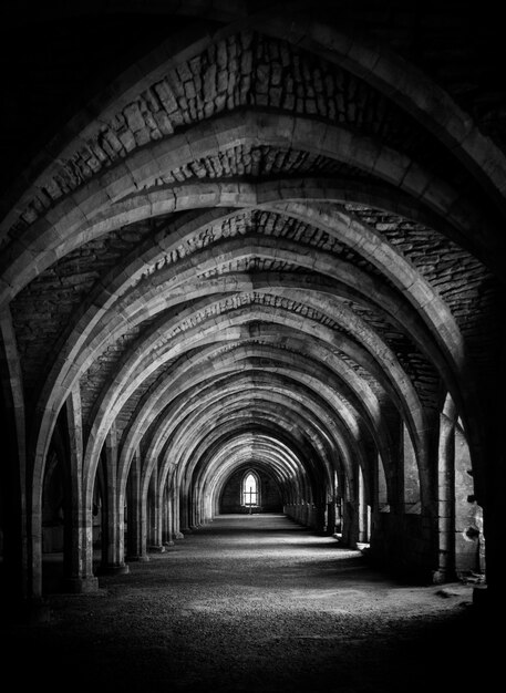Tiro vertical del pasillo en blanco y negro en la cripta en Fountains Abbey.
