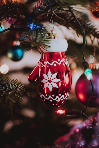 Tiro vertical del primer de un ornamento en forma de guante de Navidad que cuelga del árbol