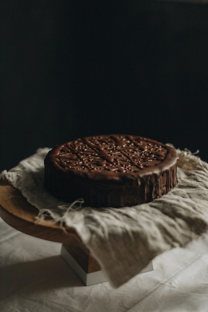 Tiro vertical selectivo del primer del pastel de chocolate en una tela en una mesa redonda