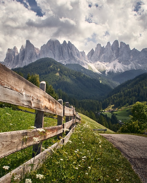Tiro vertical de una valla de madera con altos acantilados rocosos en Funes Valley, St. Italy
