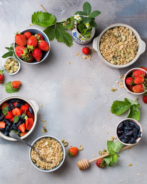 Tiro vertical vertical de cuencos llenos de avena, fresas y frutas azules