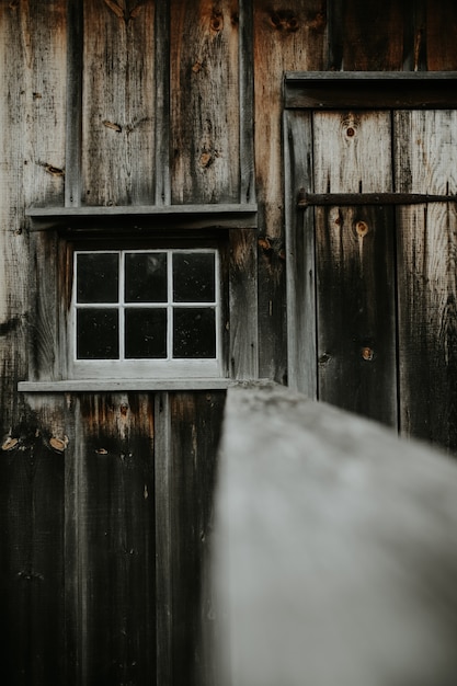 Tiro vertical de un viejo cobertizo de madera con una pequeña ventana blanca