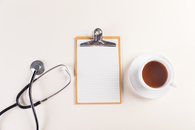 Tiro de vista superior de un bloc de notas, estetoscopio médico y una taza de té caliente