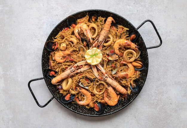 Tiro de vista superior de deliciosa paella con mariscos y aros de cebolla