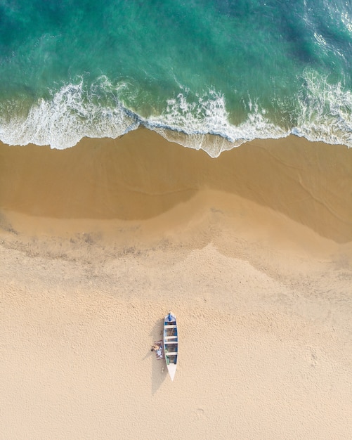 Tiro de vista superior de personas cerca de un barco en la arena de la playa de Varkala