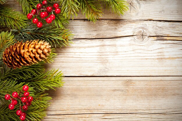 Tiro de vista superior de ramas de árbol de Navidad con muérdago y una piña sobre una superficie de madera