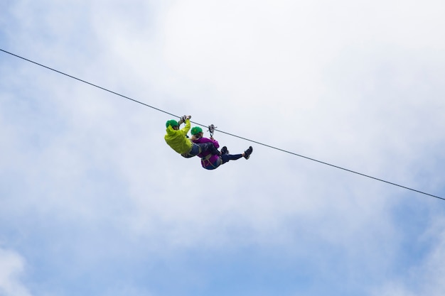 Tirolesa turística aventurera contra el cielo nublado