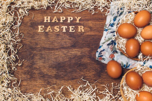 Título feliz de Pascua cerca de los huevos de gallina en cuencos en material floreado entre la malla a bordo